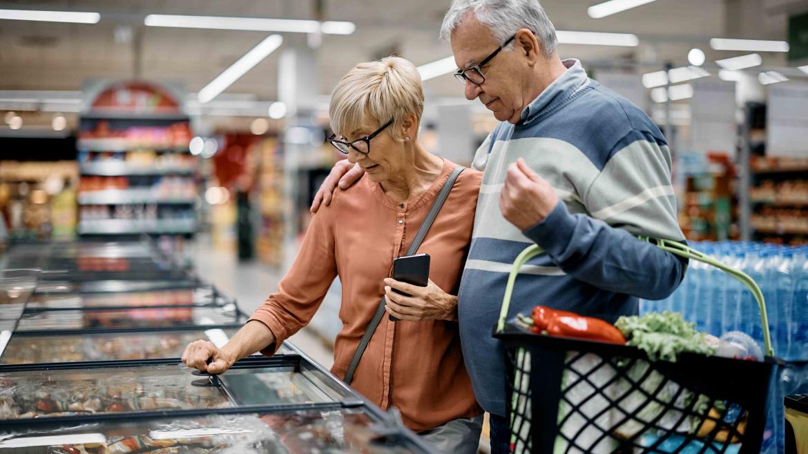 Zwei ältere Menschen stehen im Supermarkt vor der Gefriertruhe