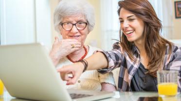Junge Frau zeigt Seniorin etwas am Laptop zu digitale Vorsorge