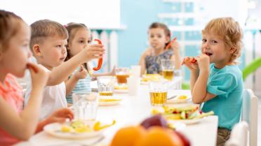 Kindergartenkinder sitzen am Tisch und essen