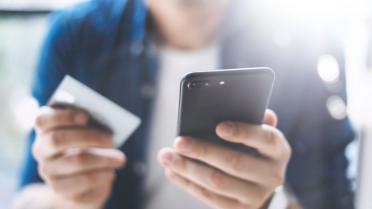 Mann mit Smartphone und Kreditkarte in der Hand zu Artikel: In-App-Käufe - 5 Dinge, die Sie wissen sollten