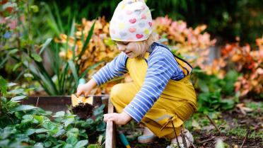 Kind mit Schaufel an Gemüsebeet
