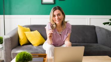Frau Sofa mit Laptop auf Tisch lächelt in Kamera