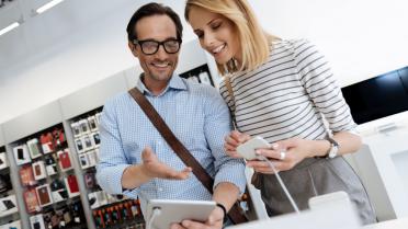 Mann mit Tablet, Frau mit Smartphone in Hand in Handyshop