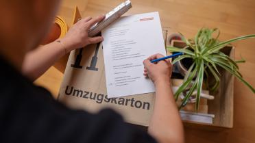 Umzugskarton mit Checkliste, Person im Hintergrund