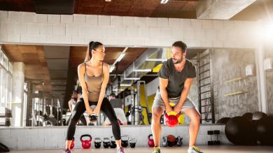 Mann und Frau mit Gewichten in Fitnessraum
