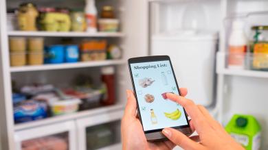 Digitale Einkaufsliste erstellen vor geöffnetem Kühlschrank