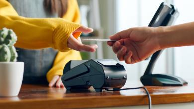 Hand reicht an Tresen Kreditkarte zur Zahlung