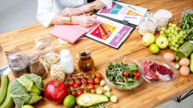 Diätassistentin erstellt Plan, viel gesunde Lebensmittel auf Tisch