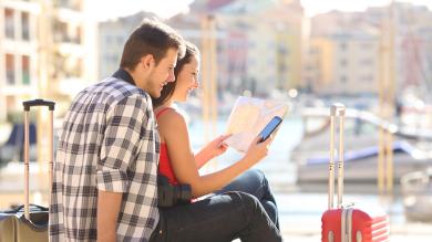 Paar mit Koffer im Urlaub schaut auf Straßenkarte