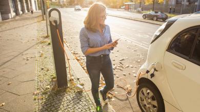 Frau mit Elektroauto an Ladesäule