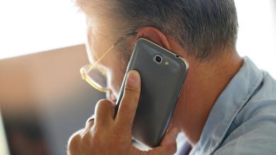 Schmuckbild: Mann mit Smartphone am Ohr, von schräg hinten zu sehen.