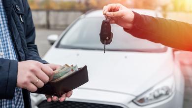 Mann mit offenem Portemonnaie, zweiter Mann mit Autoschlüssel vor Auto zu Artikel: Gebrauchtwagenverkauf online: Preiseinschätzung nicht bindend