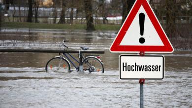 Überflutete Landschaft mit Fahrrad an Geländer angekettet zu Artikel: Ihre Möglichkeiten bei in Hochwassergebiet geplantem Urlaub