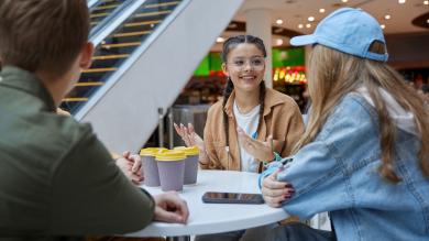 Jugendliche sitzen in Einkaufszentrum mit Kaffeebechern