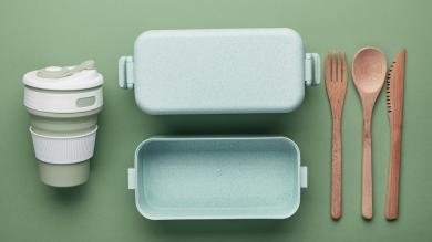 Schmuckbild: Plastik- und Holzgeschirrteile nebeneinanderliegend vor grünem Hintergrund