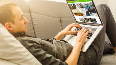 Mann auf Sofa mit Laptop zu Artikel: Phishingversuch beim Autokauf im Internet 