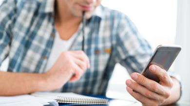 Mann mit Smartphone und Block zum Rechnen