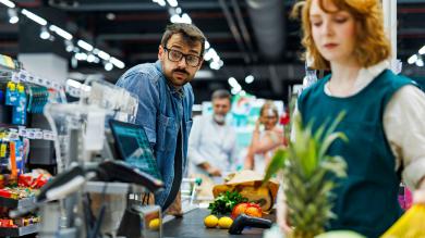 Mann an der Supermarktkasse wundert sich über den Preis