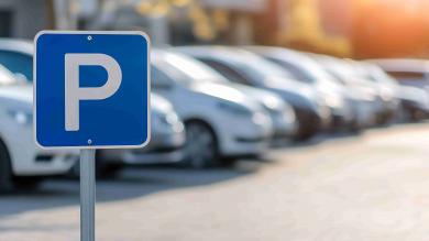 Parkplatzschild im Vordergrund im Hintergrund Autos verschwommen