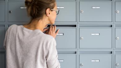 Nachsendeauftrag Frau schaut in Briefkasten