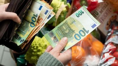 Jemand bezahlt mit einem 100 Euro Schein Waren an der Supermarktkasse. Blick von oben ins Portmonnaie