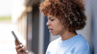 Mädchen schaut verstört auf ihr Telefon