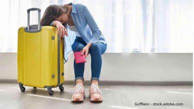 Frau stützt sich am Flughafen auf gelben Koffer Flug ist verspätet