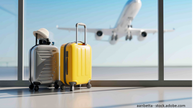 Koffer stehen alleine am Flughafen. Flieger hebt im Hintergrund  ab.