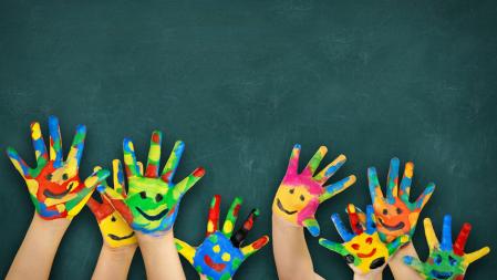 Bunt angemalte Kinderhände vor Schultafel