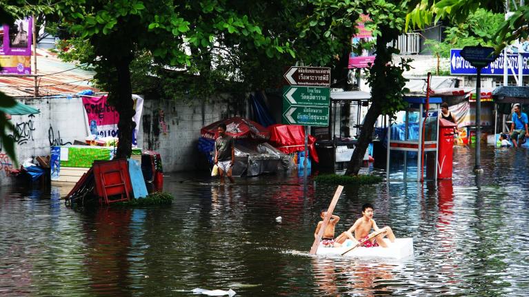 Zwei Jungs paddeln in überfluteter Stadt