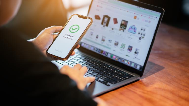 Mann nutzt Smartphone um Onlineeinkauf zu bezahlen