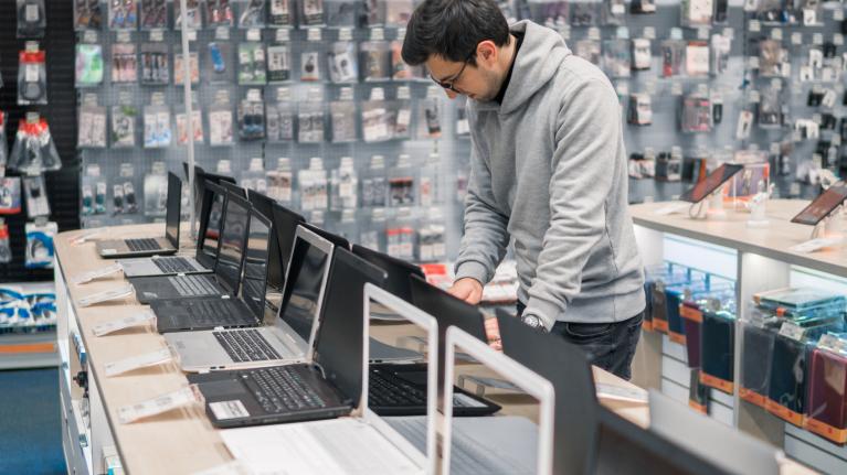Mann will Laptop kaufen im Laden
