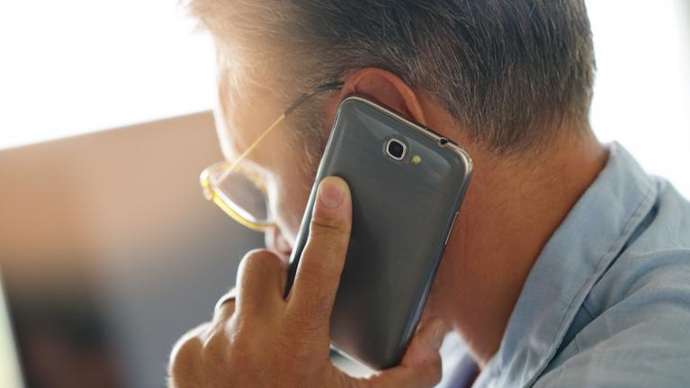Schmuckbild: Mann mit Smartphone am Ohr, von schräg hinten zu sehen.