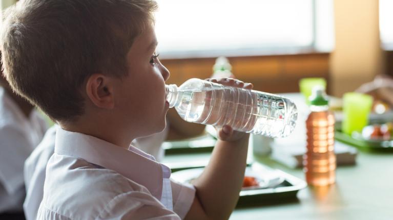 Junge trinkt Wasser aus Flasche in Schule
