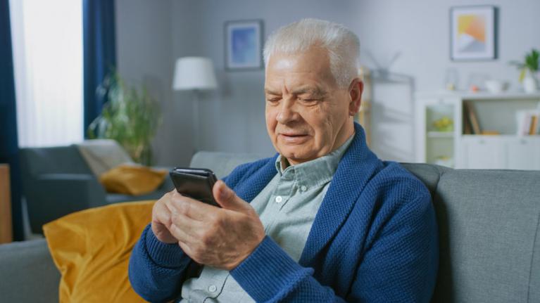 Rentner auf Sofa mit Handy