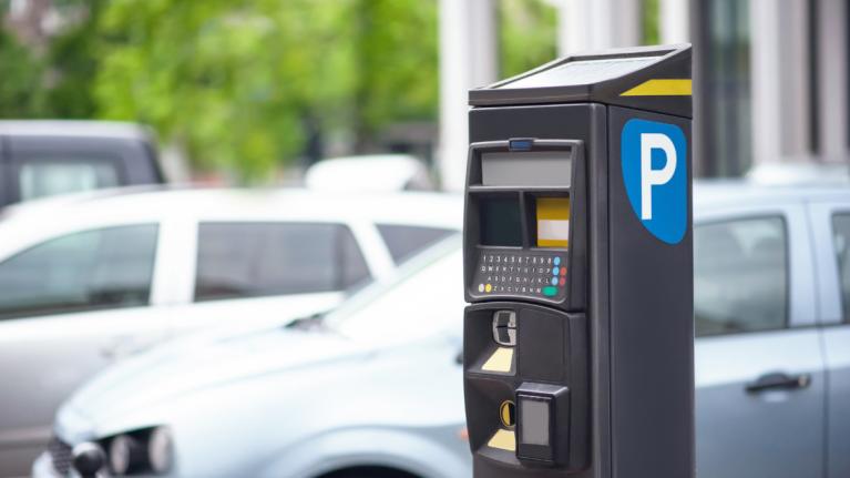 Parkautomat mit Autos im Hintergrund