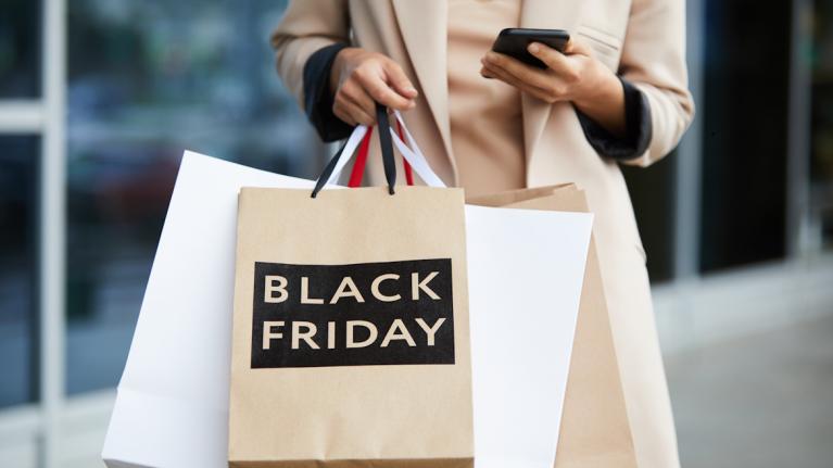 Frau mit Einkaufstüten. Auf einer steht Black Friday