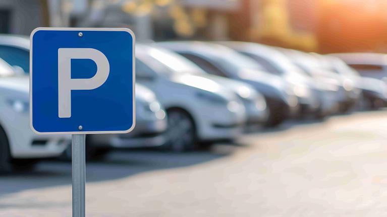 Parkplatzschild im Vordergrund im Hintergrund Autos verschwommen