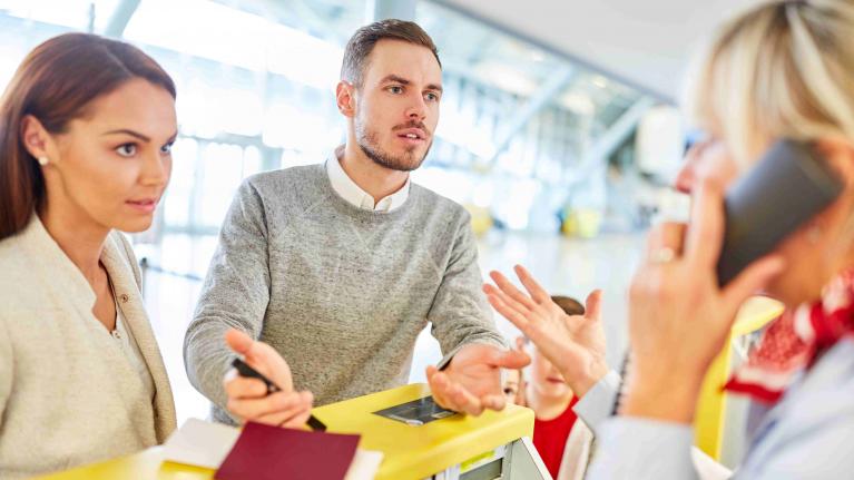 Familie diskutiert am Airline Schalter Flughafen mit Servicepersonal