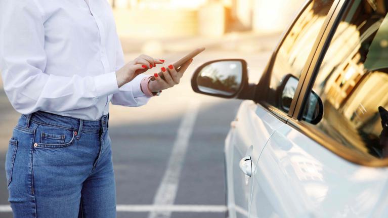 Frau macht mit Handy Carsharingauto auf