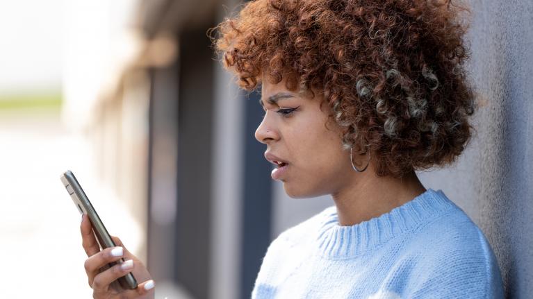 Mädchen schaut verstört auf ihr Telefon