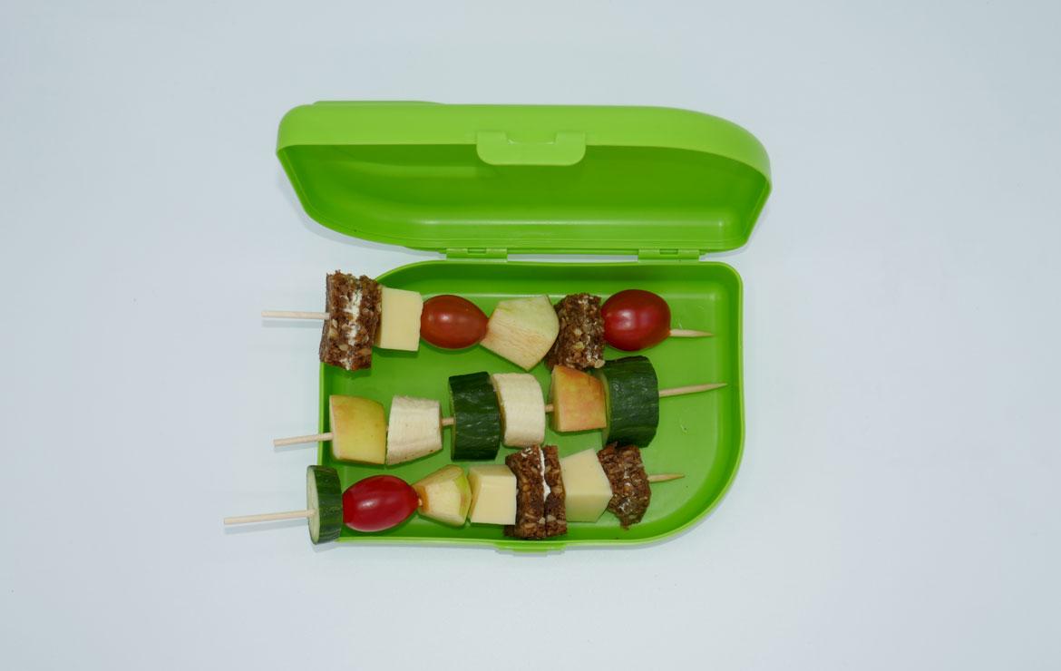Brotbox mit bunten Spießen mit Gemüse, Obst und Brot