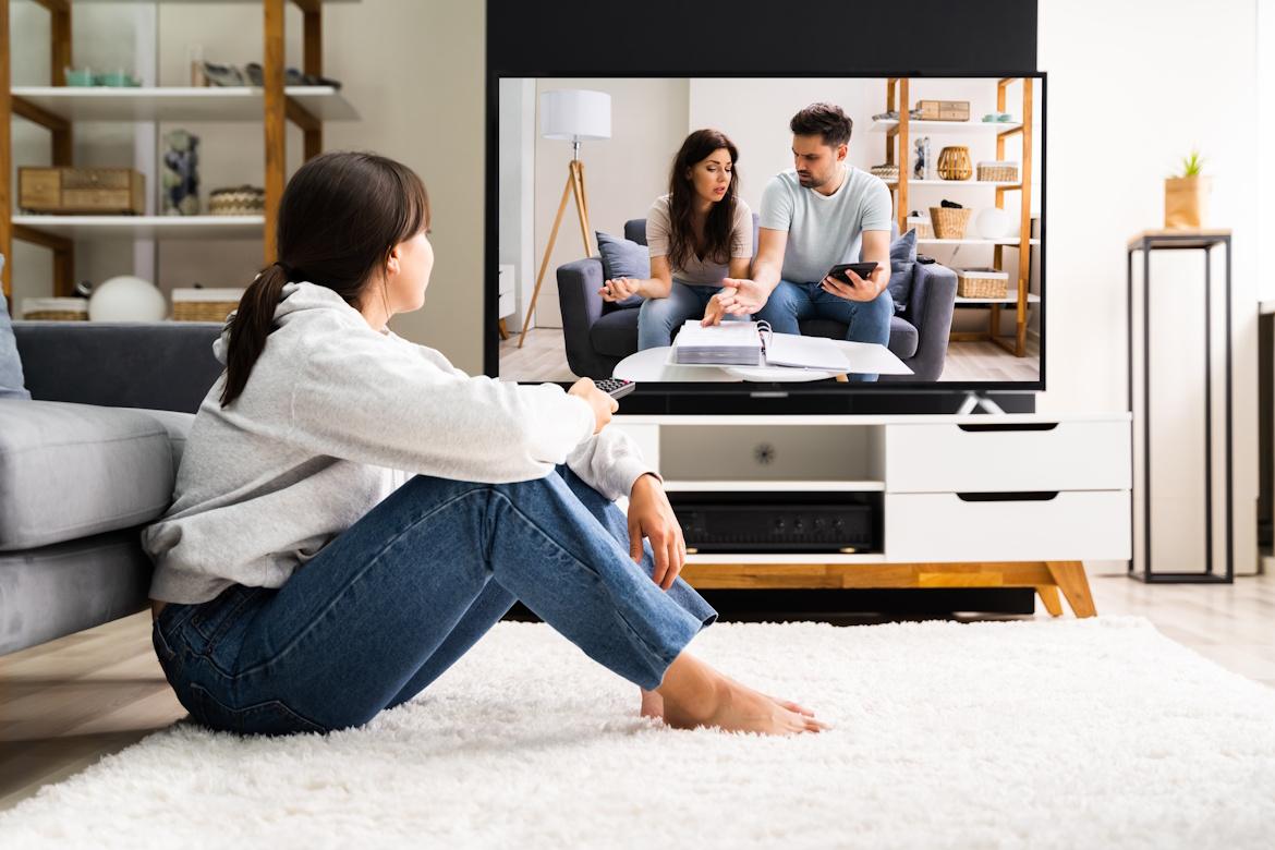 Frau auf Boden sitzend schaut Fernsehen