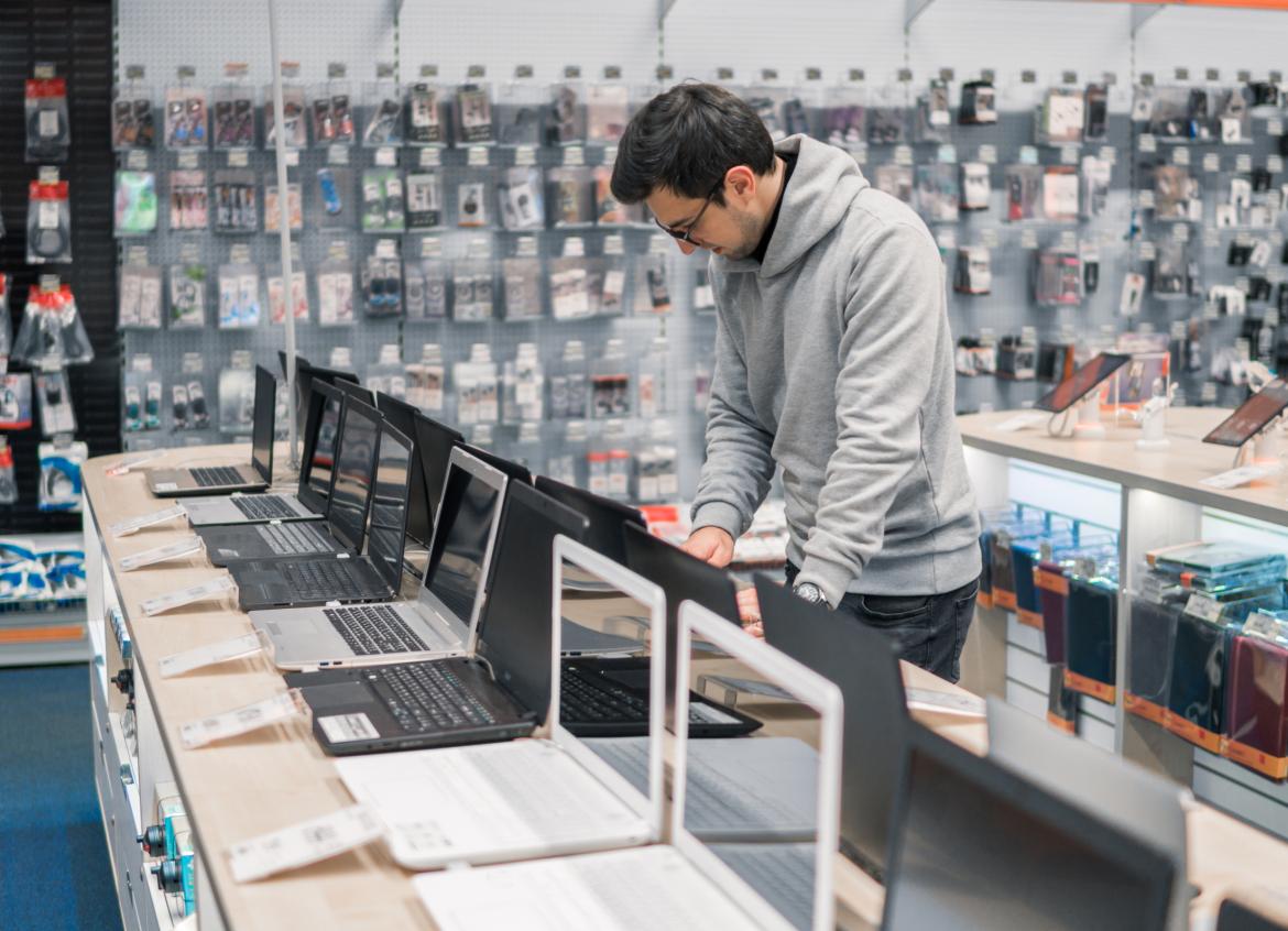 Mann will Laptop kaufen im Laden