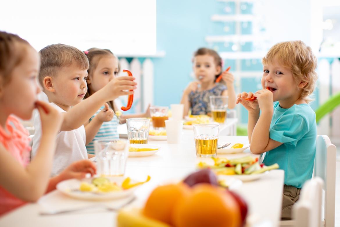 Kindergartenkinder sitzen am Tisch und essen
