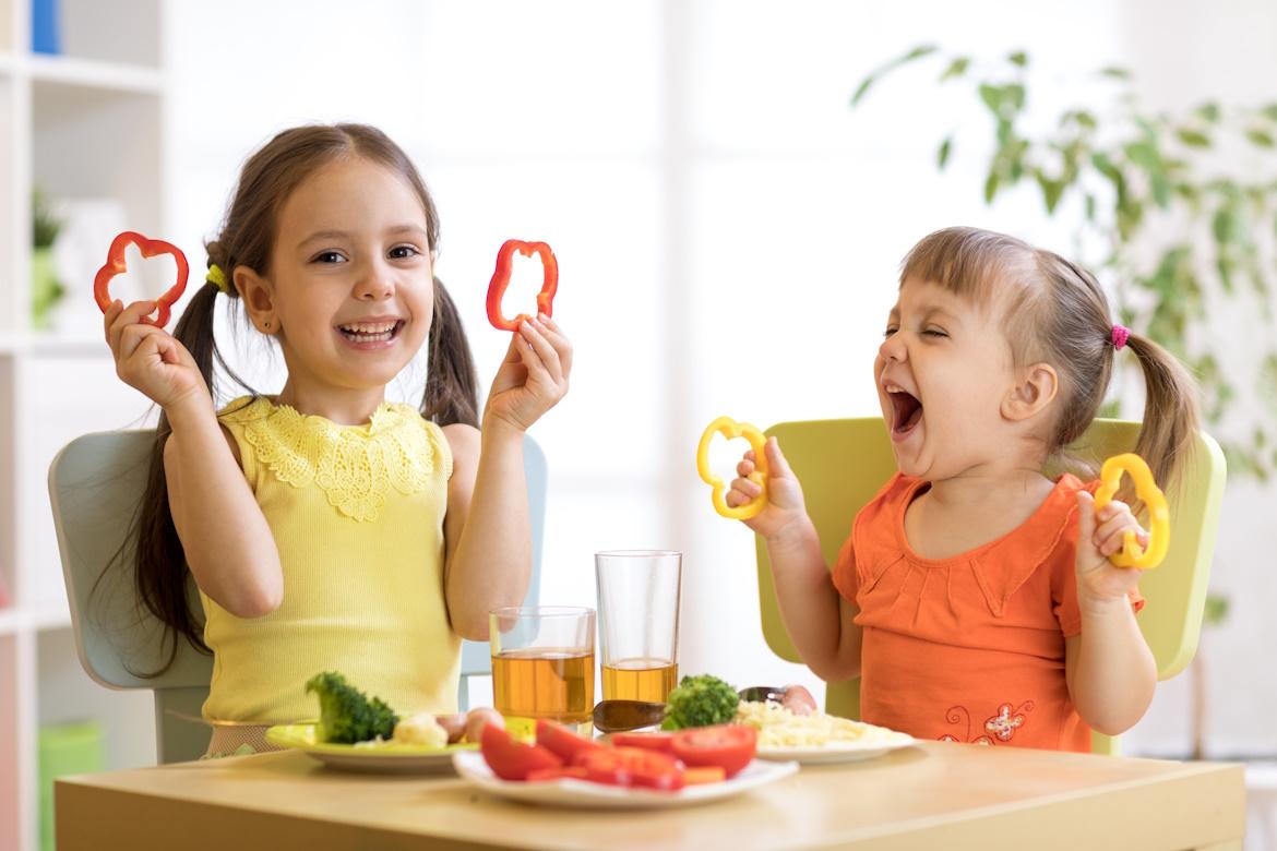 Zwei fröhliche Kinder essen gesundes Essen im Kindergarten