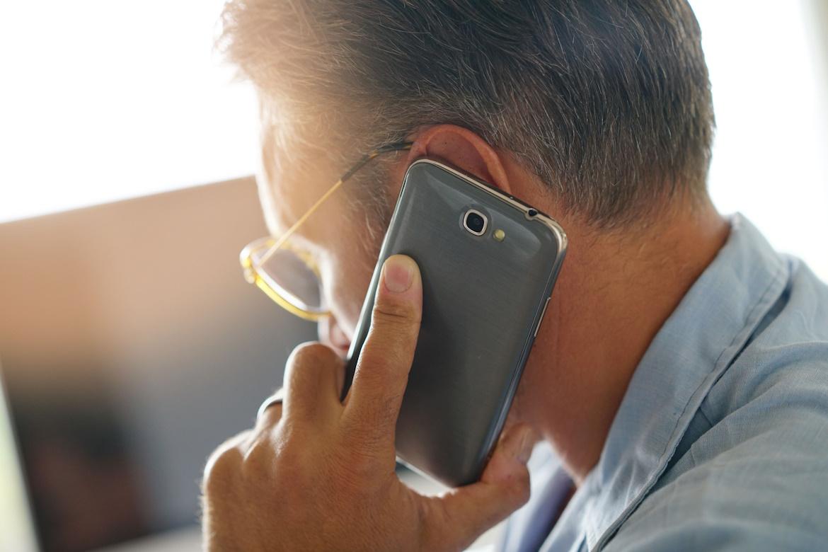 Schmuckbild: Mann mit Smartphone am Ohr, von schräg hinten zu sehen.