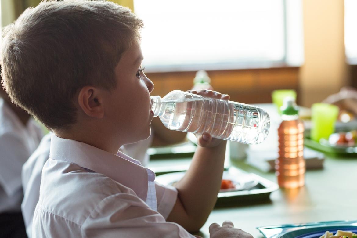 Junge trinkt Wasser aus Flasche in Schule