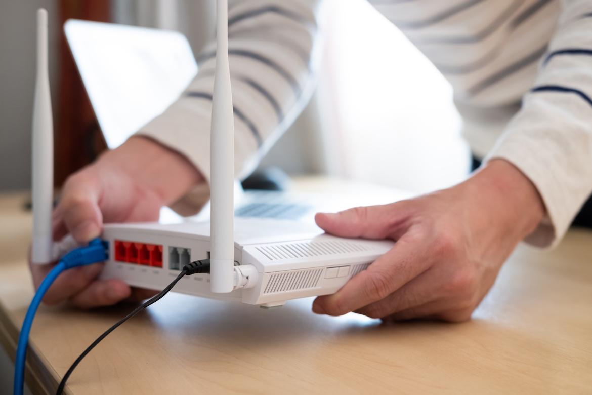 Mensch steckt Kabel in Glasfasermodem