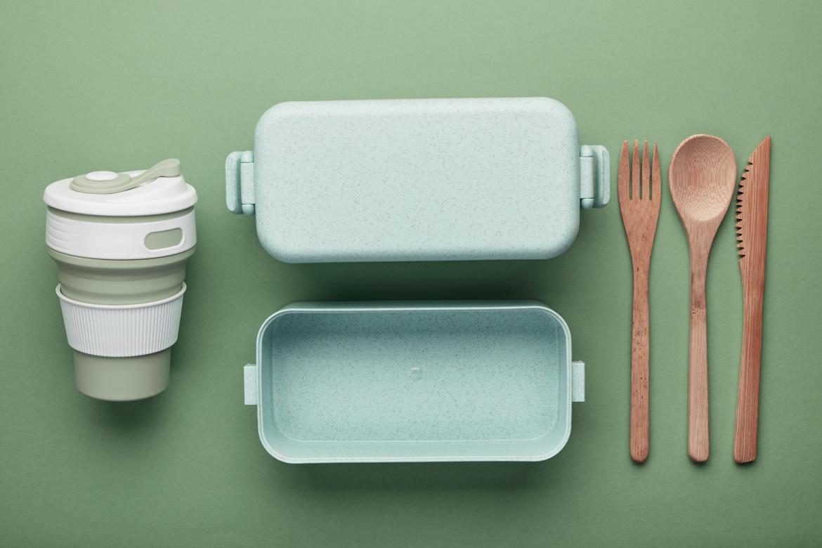 Schmuckbild: Plastik- und Holzgeschirrteile nebeneinanderliegend vor grünem Hintergrund